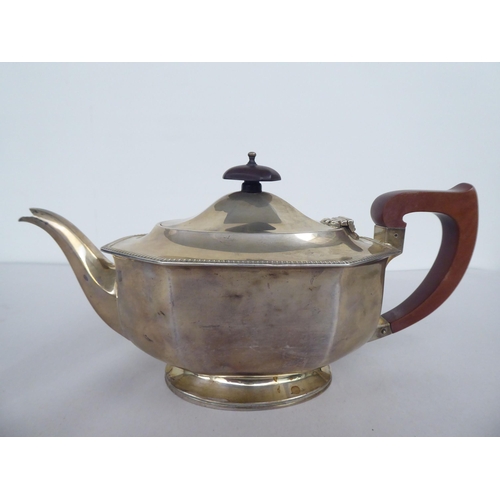 63 - A silver teapot of panelled, oval, octagonal form with a swept spout, insulated handle and knop on t... 