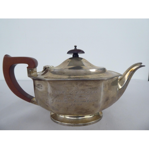 63 - A silver teapot of panelled, oval, octagonal form with a swept spout, insulated handle and knop on t... 