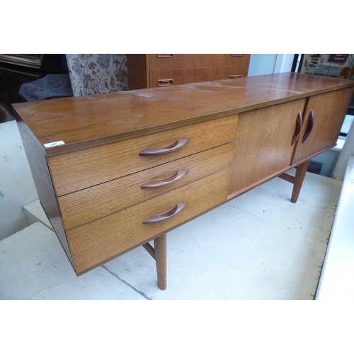 66 - An Avalon teak sideboard with a bank of three offset drawers and a pair of adjacent sliding doors, r... 