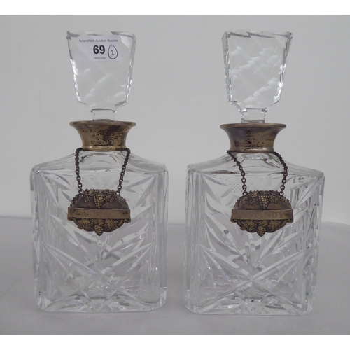 69 - A pair of silver coloured clear glass decanters of shouldered, box design with silver decanter label... 