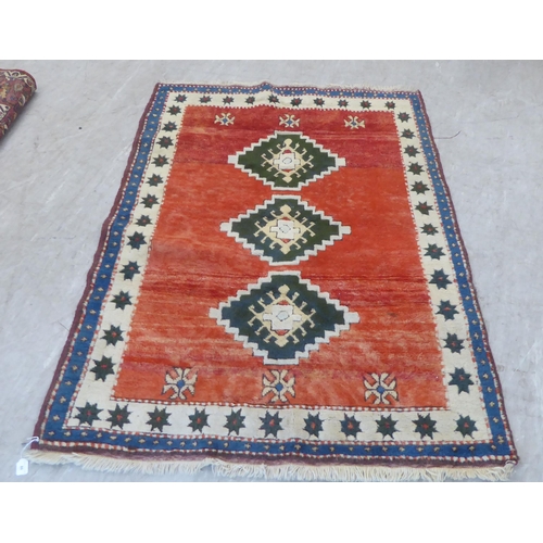 80 - A Turkish rug, decorated with three diamond motifs, on a mainly red ground  54