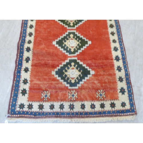 80 - A Turkish rug, decorated with three diamond motifs, on a mainly red ground  54