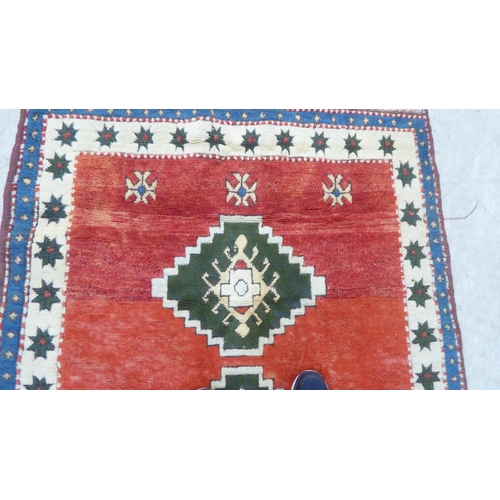 80 - A Turkish rug, decorated with three diamond motifs, on a mainly red ground  54