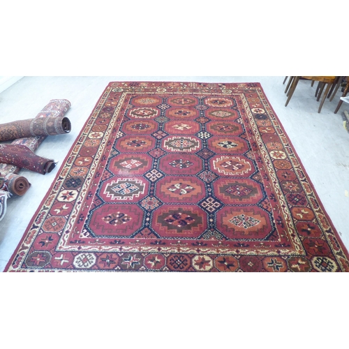 83 - A Persian design woollen carpet, decorated with repeating box design, stylised motif centre, bordere... 