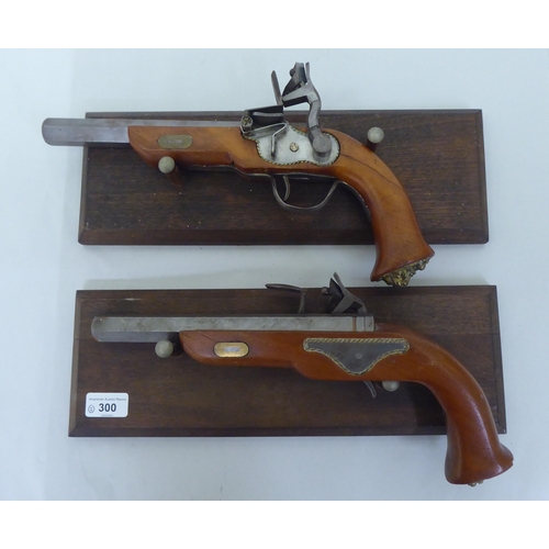 300 - A pair of replica 19thC style duelling pistols, on display plinths