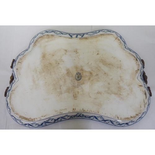 101 - A modern Continental china serving tray of irregular outline with opposing east metal handles, decor... 