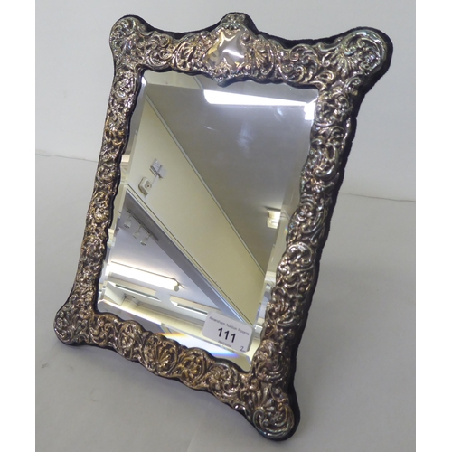 111 - A Victorian style dressing table mirror, the bevelled plate set in an overlaid and embossed silver f... 