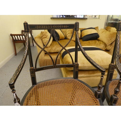 121 - A pair of early 19thC style black painted and gilded beech framed chairs, each having a curved crest... 