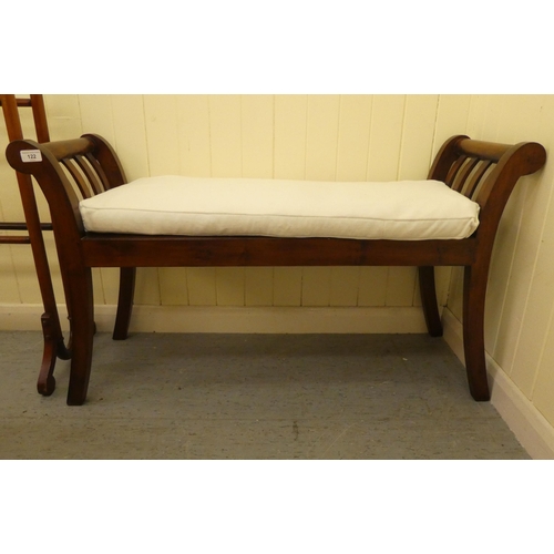 122 - A 19thC style mahogany framed window seat with low, scrolled ends and a solid base and cream fabric ... 