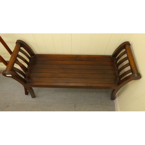 122 - A 19thC style mahogany framed window seat with low, scrolled ends and a solid base and cream fabric ... 