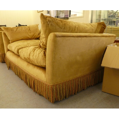 123 - A modern box settee with a low back and enclosed arms, upholstered in tasselled old gold coloured fa... 