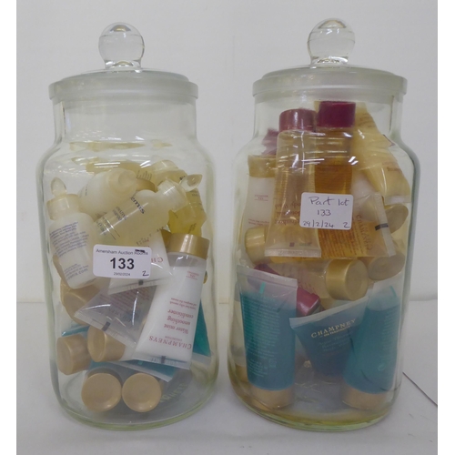 133 - A vast quantity of creams and shampoos samples from Elemis and Champneys, in two covered glass jars