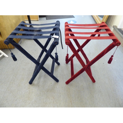 139 - A pair of luggage stands, respectively finished in navy blue and pillar box red fabric, raised on ta... 