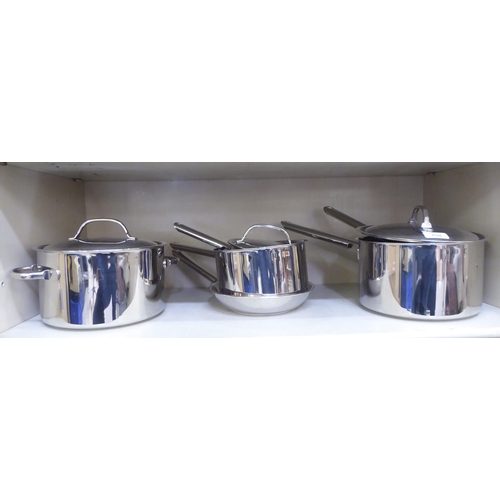 150 - A graduated set of five stainless steel saucepans with lids and a frying pan