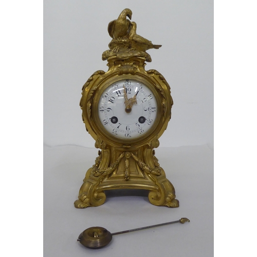 189 - A reproduction of a 19thC gilt metal cased mantel clock of balloon design, surmounted by a pair of d... 