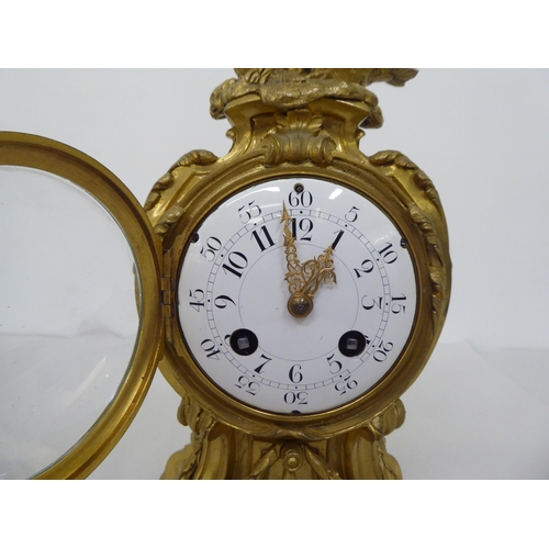 189 - A reproduction of a 19thC gilt metal cased mantel clock of balloon design, surmounted by a pair of d... 