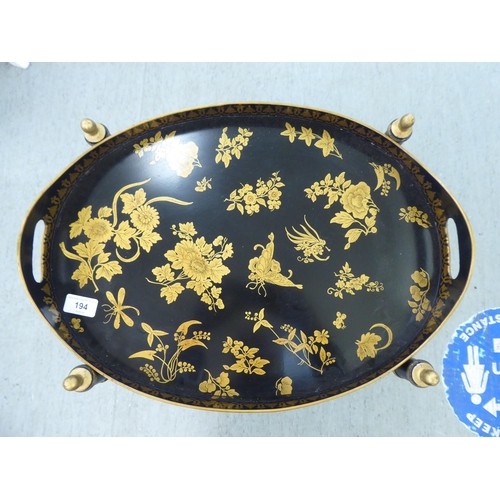 194 - A Regency style black painted and gilded oval tray table and undertier, on a foldable stand  19... 