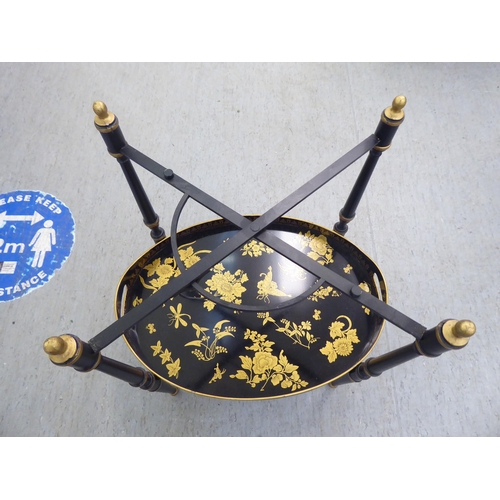 194 - A Regency style black painted and gilded oval tray table and undertier, on a foldable stand  19... 