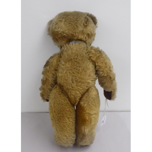 21 - A mid 20thC mohair covered Teddy bear with mobile limbs, a blue ribbon and growler  20