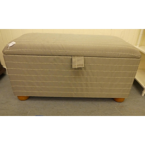 211 - A modern box ottoman, finished in horizontal striped, silver coloured material, the hinged lid enclo... 