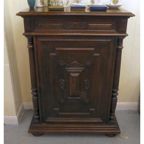 246 - A late 19thC Continental oak cabinet with a drawer and panelled door, raised on bun feet  43