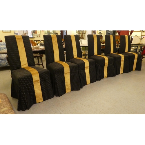 253 - A set of six black and gold fabric covered dining chairs, raised on stained beech legs 