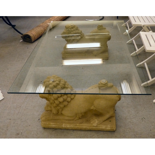 255 - A modern coffee table with a plate glass top, raised on stone plinths, fashioned as lions  17