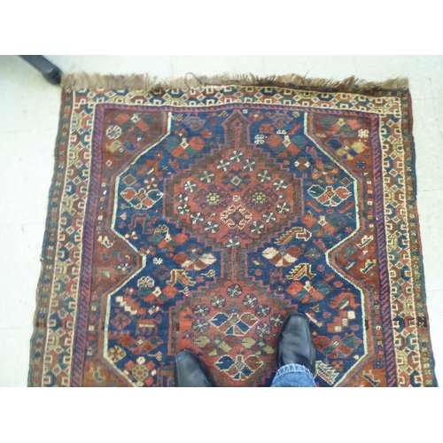 263 - A Persian rug, decorated with triple gul motifs, on a red and blue ground  45