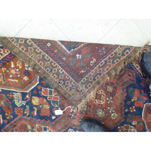 263 - A Persian rug, decorated with triple gul motifs, on a red and blue ground  45