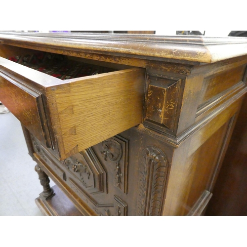 264 - A late 19thC Continental oak cabinet with a drawer and a carved panelled door, raised on turned legs... 