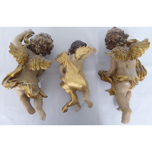 44 - Three overpainted composition cherubic figures  largest 14