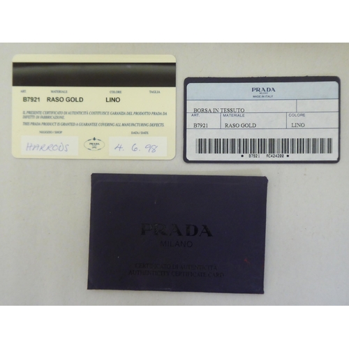 90 - Three Prada fabric handbags, viz. a Raso Gold 1998 with dust cover, one in cream coloured net with p... 