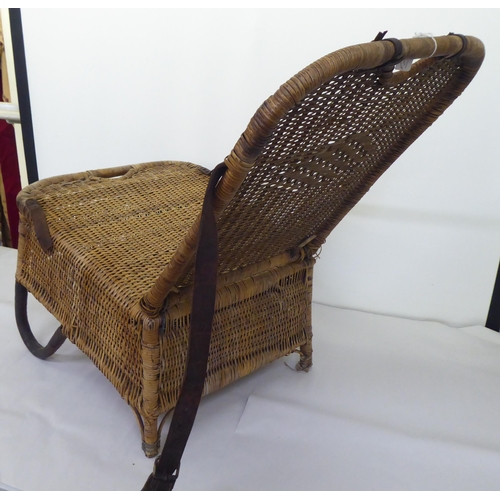 97 - A late Victorian/Edwardian woven split cane folding campaign/anglers chair with a storage compartmen... 