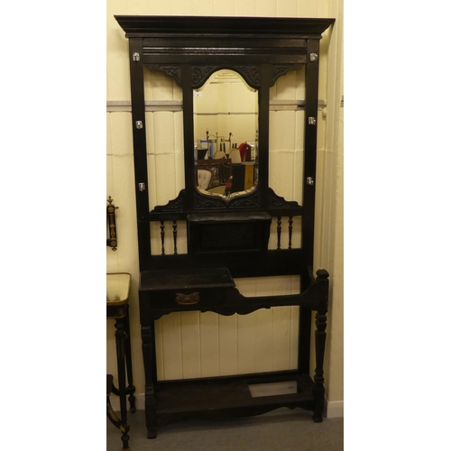 99 - A late Victorian black stained and carved oak hallstand, incorporating a bevelled mirror and an offs... 