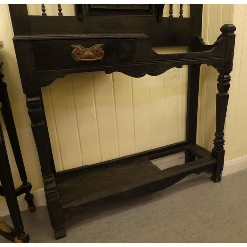 99 - A late Victorian black stained and carved oak hallstand, incorporating a bevelled mirror and an offs... 