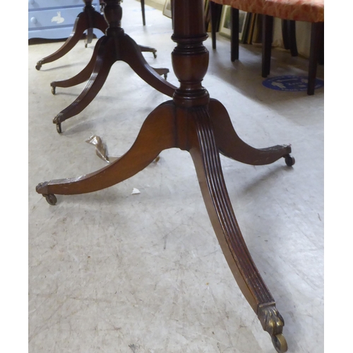 119 - A 20thC reproduction of a Regency crossbanded mahogany triple pedestal dining table with two additio... 