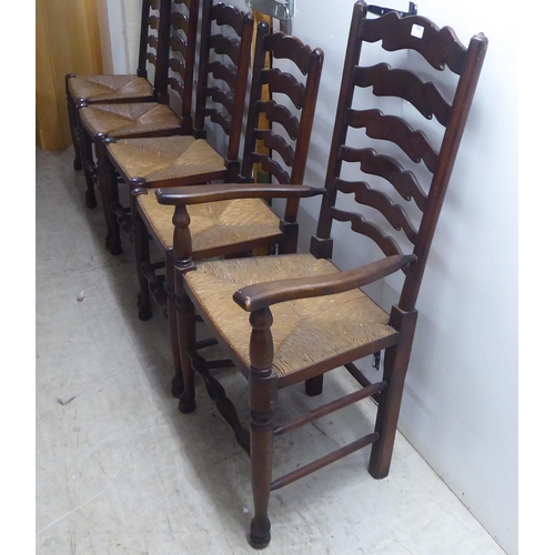 124 - A set of five 20thC Lancashire style, stained beech framed ladderback dining chairs, the rush seats ... 