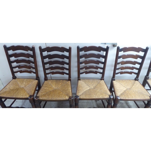 124 - A set of five 20thC Lancashire style, stained beech framed ladderback dining chairs, the rush seats ... 