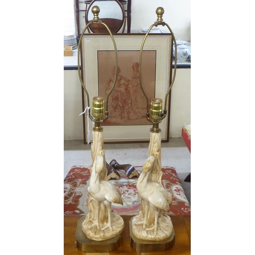 134 - A pair of mid 20thC china table lamps, fashioned as herons, on a brass plinth  19