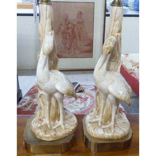 134 - A pair of mid 20thC china table lamps, fashioned as herons, on a brass plinth  19