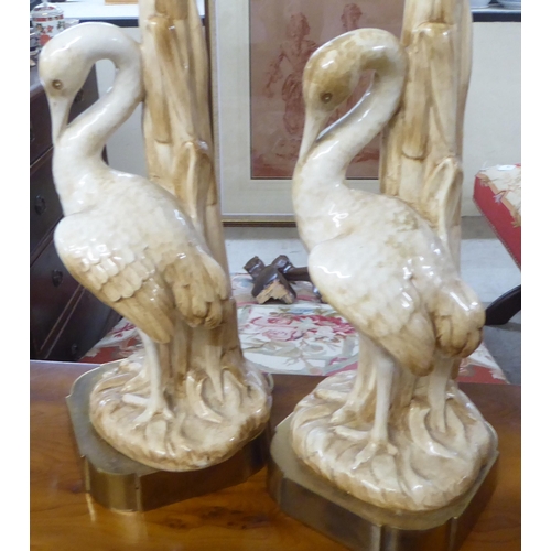 134 - A pair of mid 20thC china table lamps, fashioned as herons, on a brass plinth  19