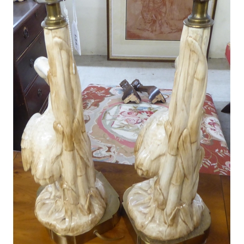 134 - A pair of mid 20thC china table lamps, fashioned as herons, on a brass plinth  19