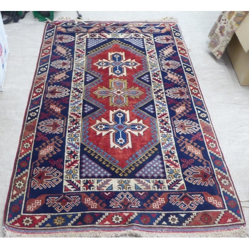 158 - A Persian rug, decorated with a central triple gul, on a red and blue ground  49