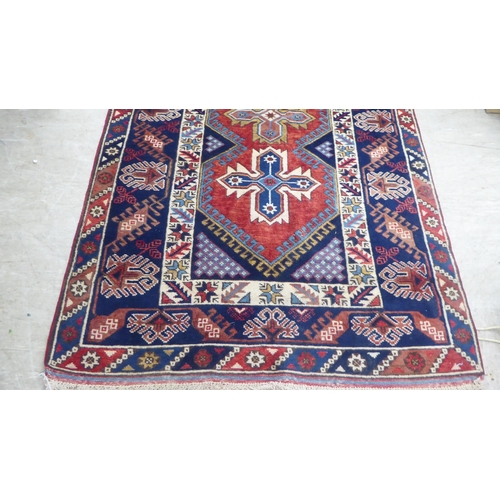 158 - A Persian rug, decorated with a central triple gul, on a red and blue ground  49