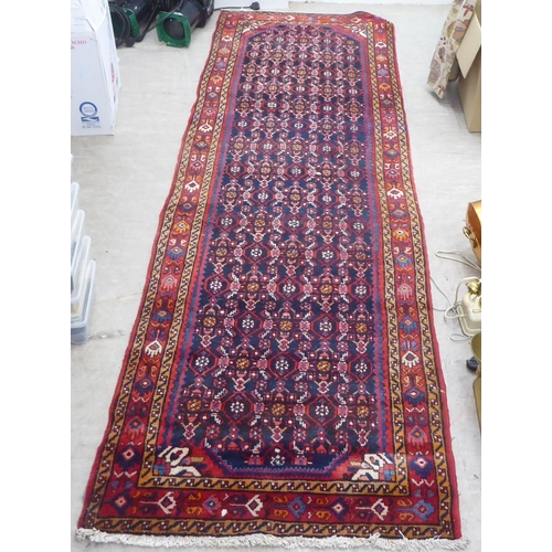 167 - A Persian runner, decorated with geometric motifs, on a red and blue ground  140