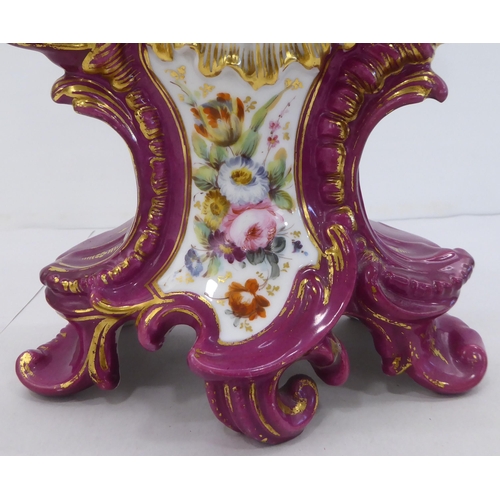 169 - A mid 20thC French mantel timepiece, , set in an ornate Rococo design china and floral overpainted c... 