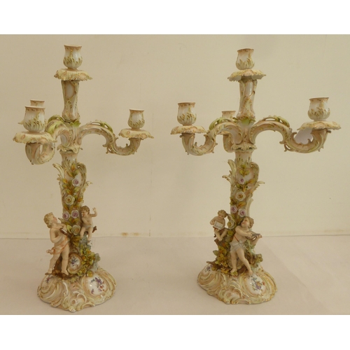 186 - A pair of late 19thC Continental porcelain triple branch candelabra, each fashioned as a tree, surmo... 