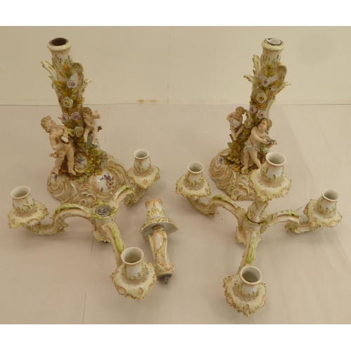 186 - A pair of late 19thC Continental porcelain triple branch candelabra, each fashioned as a tree, surmo... 