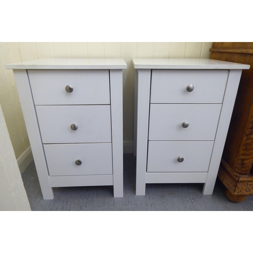 296 - A pair of modern white painted three drawer bedside chests, raised on square legs  24