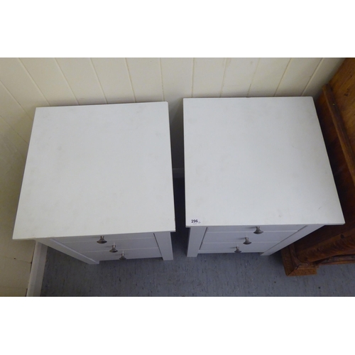 296 - A pair of modern white painted three drawer bedside chests, raised on square legs  24